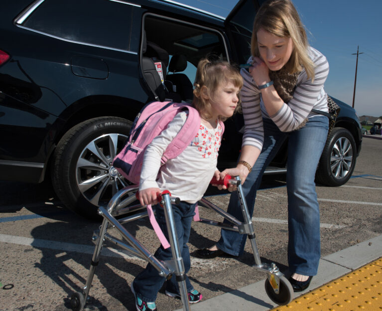 Girl with walker being helped by her mother